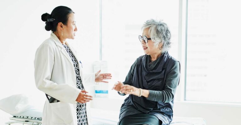 Senior female patient in discussion with doctor during check up in exam room