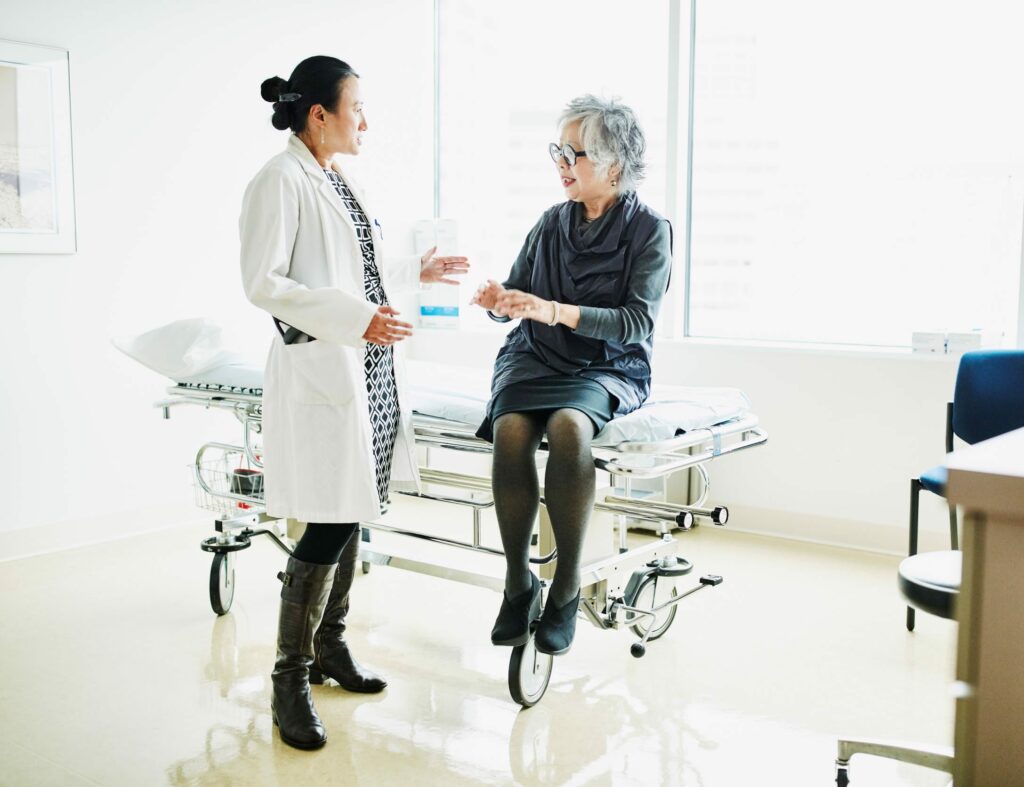 Senior female patient in discussion with doctor during check up in exam room