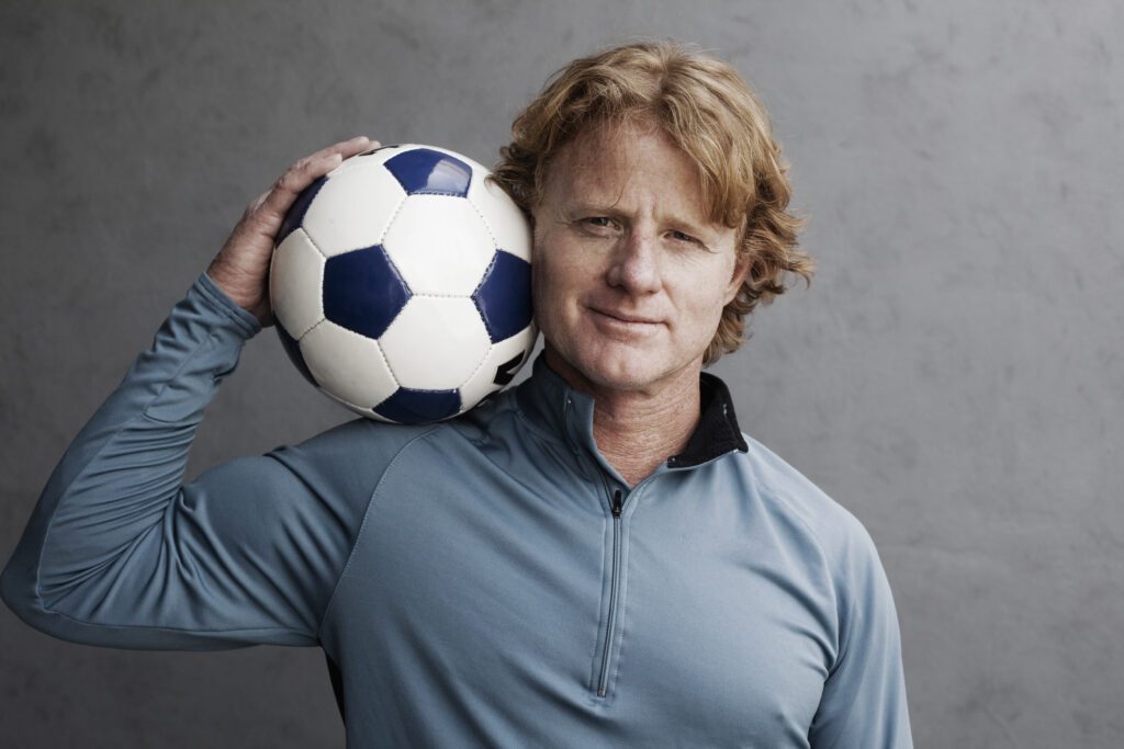 Redhead holding a soccer ball on his shoulder